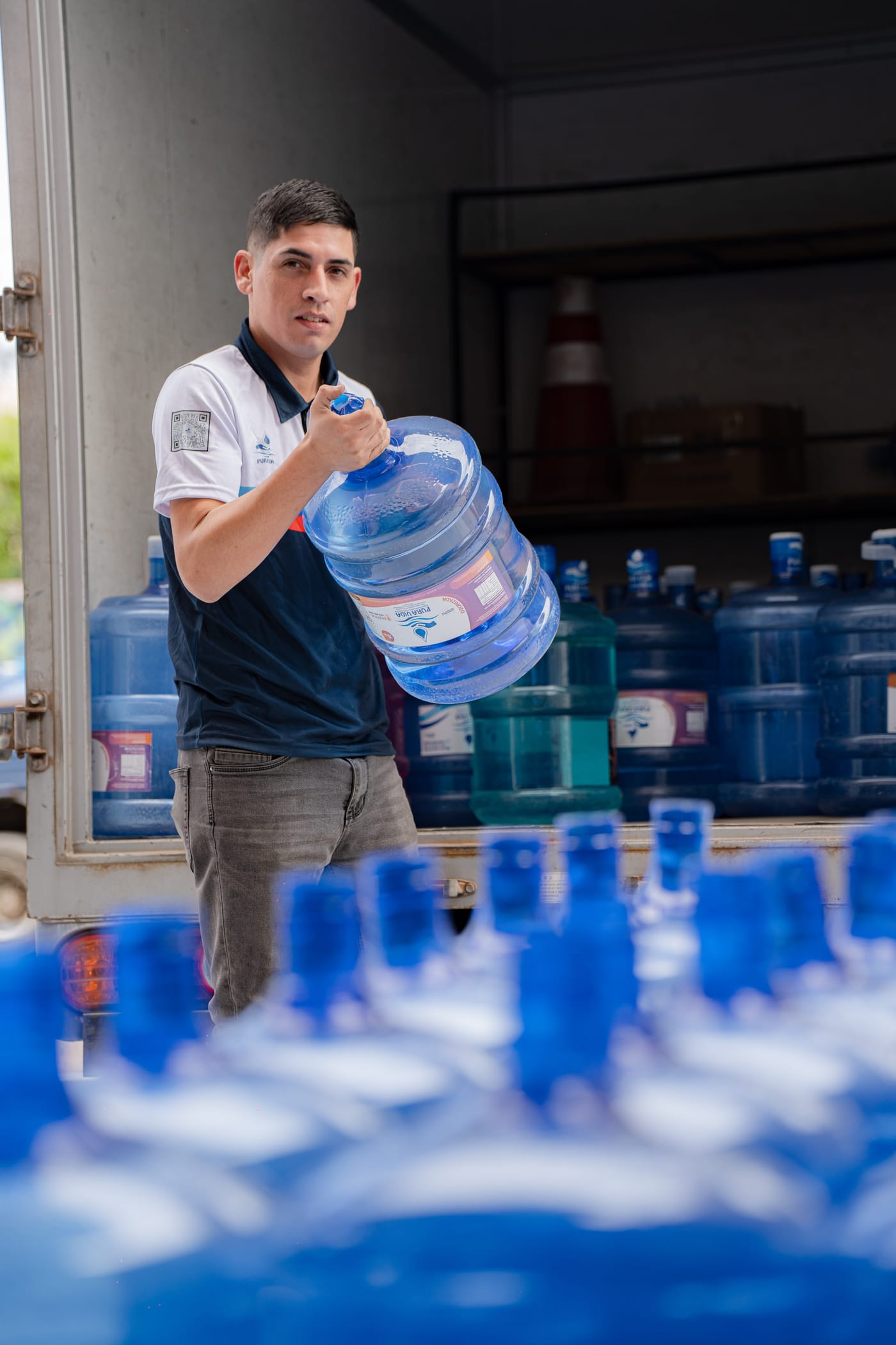 Repartidor de Pura Vida cargando un bidón de 20 litros desde el camión