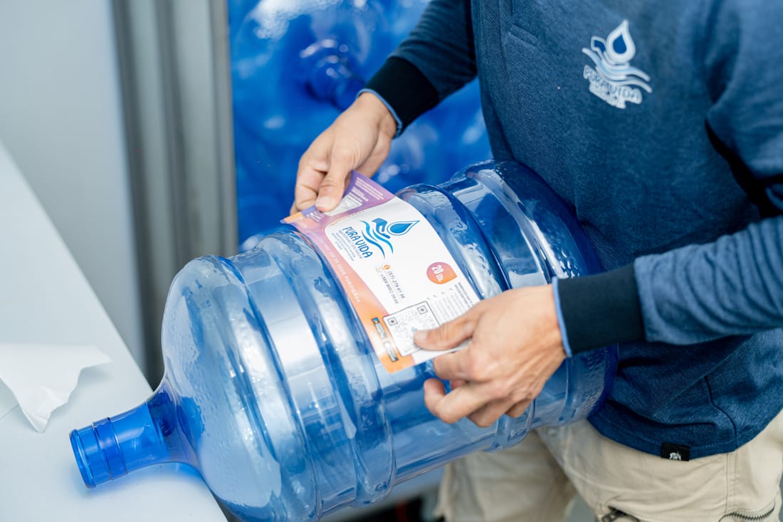 Colocación de la etiqueta en un bidón de 20 litros de Pura Vida