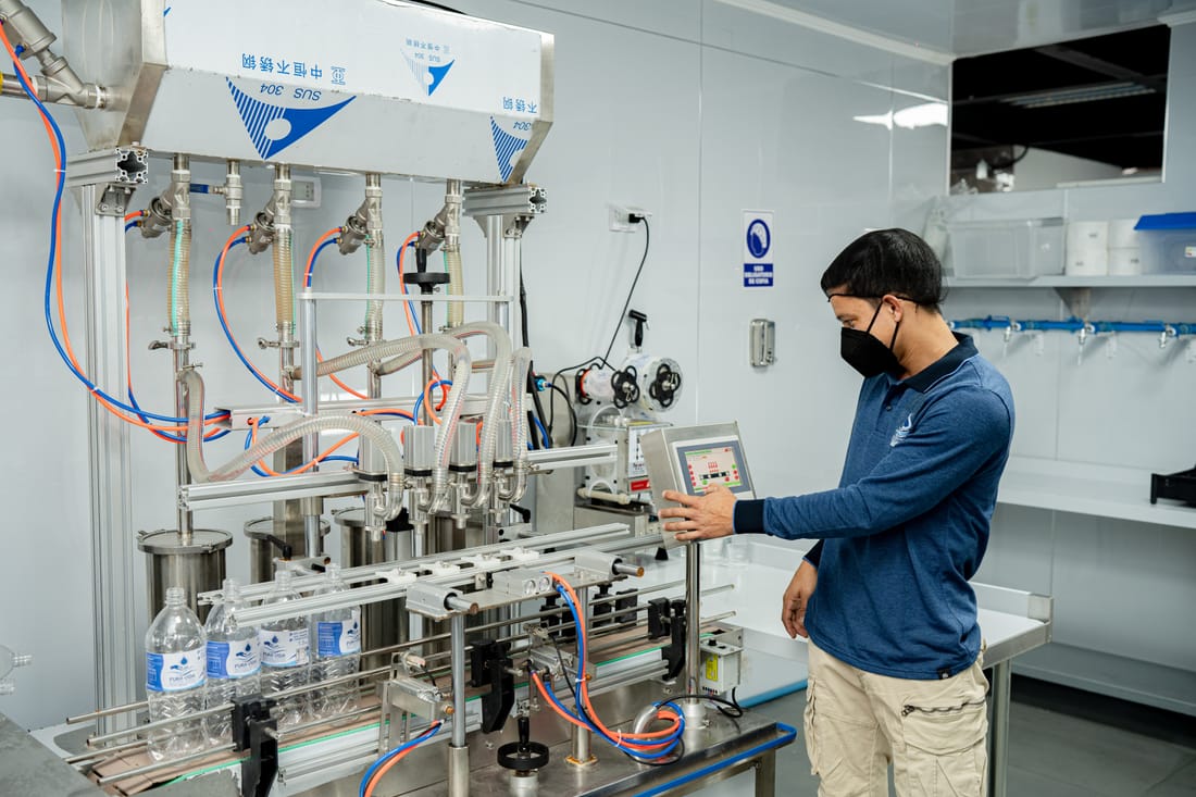 Operario de Pura Vida supervisando la línea de envasado de agua purificada