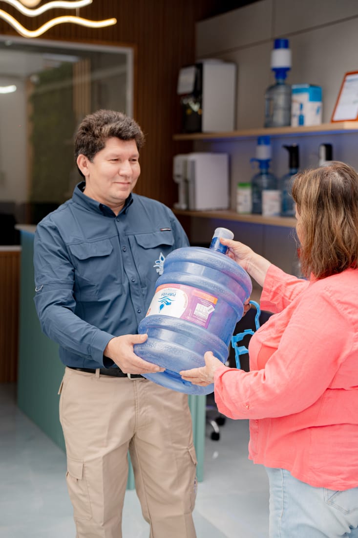 Entrega de un bidón de 20 litros a una clienta en la sala de venta de Pura Vida