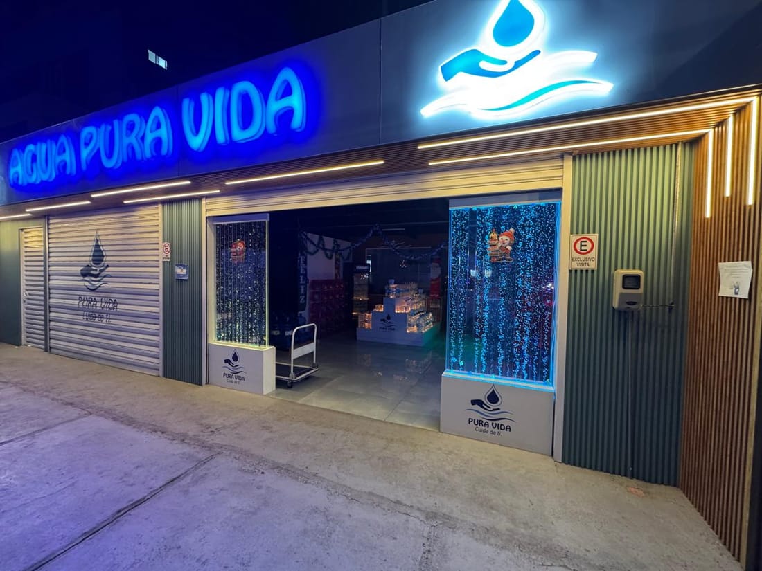 Fachada iluminada de la sala de venta Agua Pura Vida en Iquique de noche