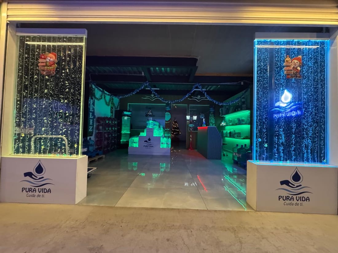 Entrada de la sala de venta de Pura Vida con paneles de agua iluminados