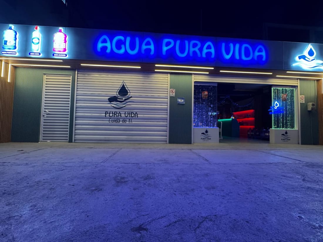 Vista exterior nocturna de la sala de venta Agua Pura Vida en Iquique